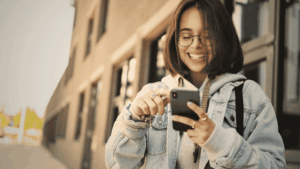 Mulher sorrindo na rua mexendo em seu celular